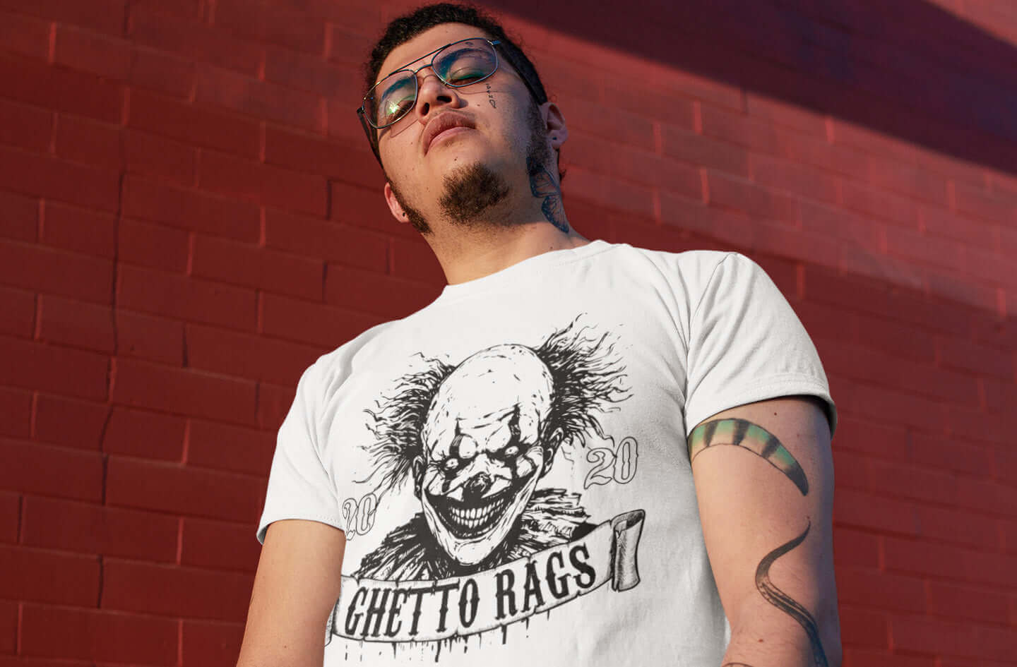 Man wearing Ghetto Rags Pennywise t-shirt in front of brick wall, showcasing urban streetwear and horror fusion.