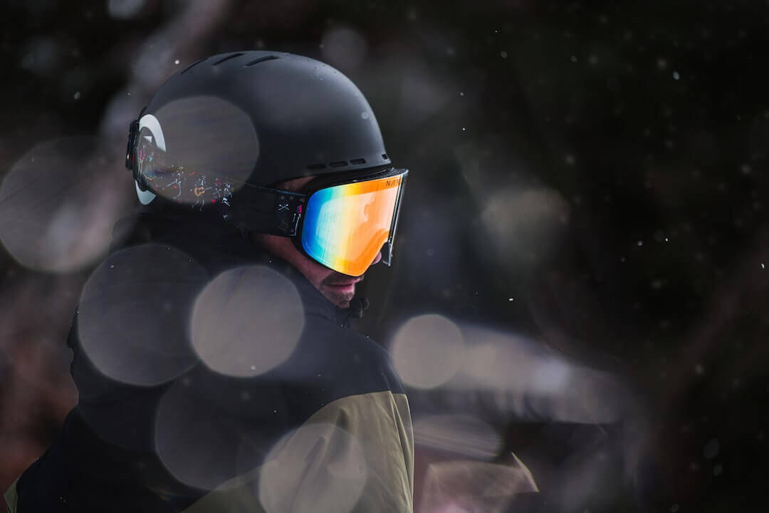 Person in reflective goggles and helmet at night, representing urban streetwear fashion style