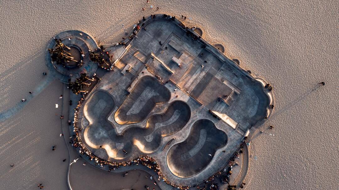 Aerial view of the bustling Venice Beach skatepark, showcasing its dynamic curves and vibrant skateboarding culture.