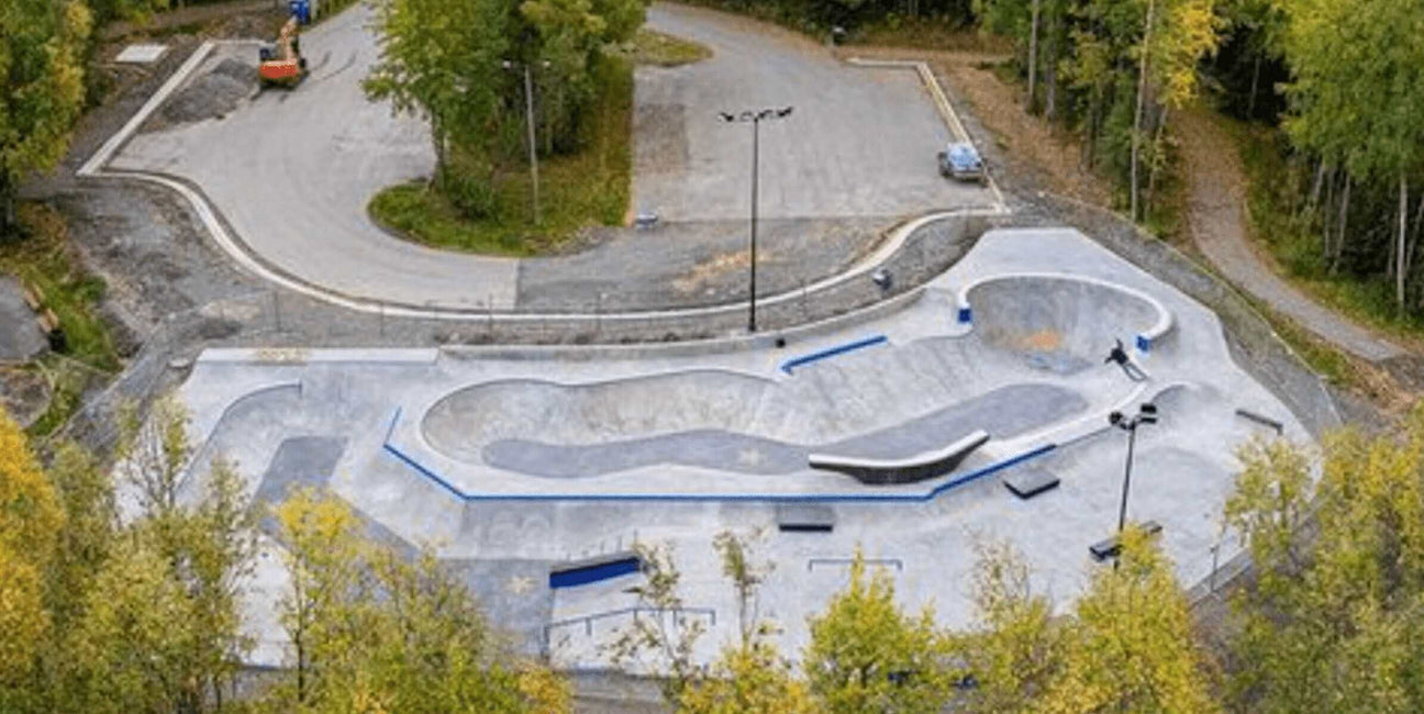 Aerial view of Taku Lake Skatepark in Anchorage, AK, showcasing new ramps and skateboarding areas surrounded by trees.